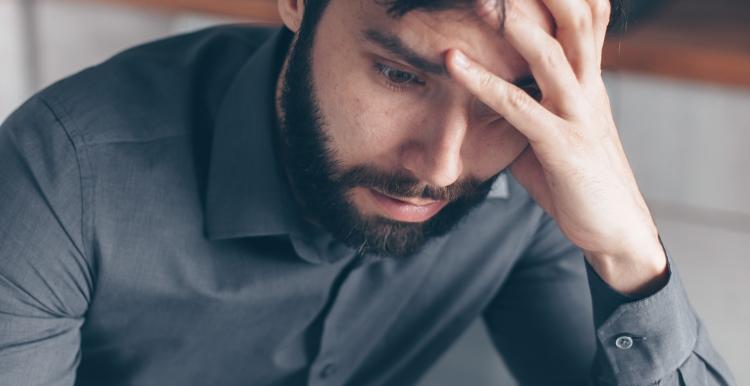 Man with glasses on head reading letter and looking confused