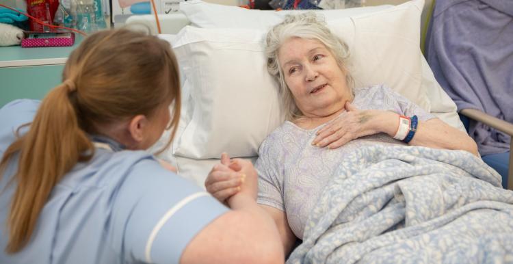 Woman in hospital bed talking to nurse