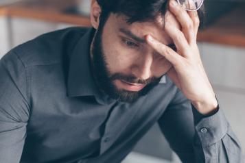 Man with glasses on head reading letter and looking confused